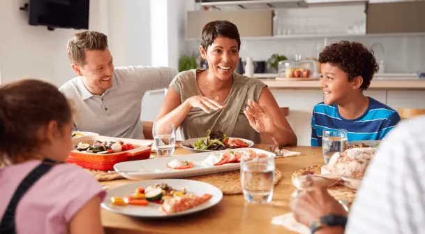 A group of adults and children eat a meal at a table.