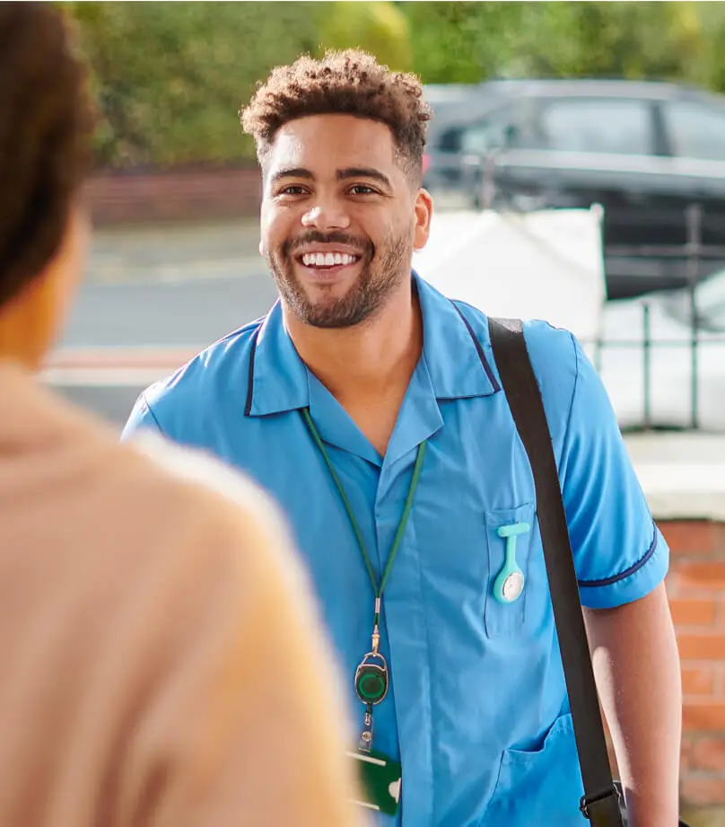 A person smile and engages with another person whose back is turned to the camera.