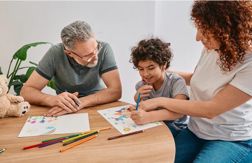 A family makes color pencil art at a table.