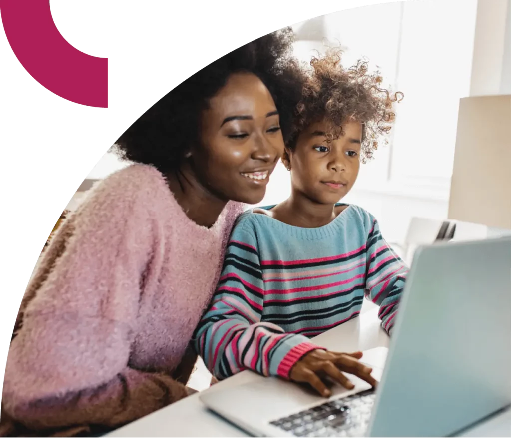 A woman and child sit and work on a laptop together