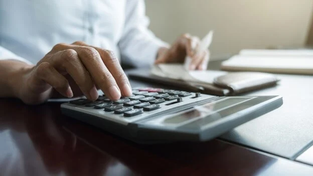 A right hand uses a calculator to input numbers.