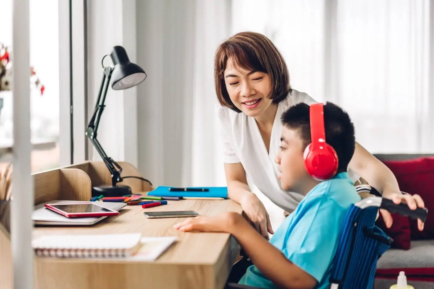A child listens to headphones while an adult looks on.