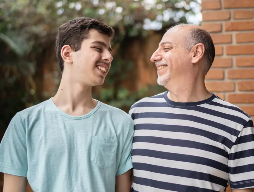 Two people smile at each other while embracing.