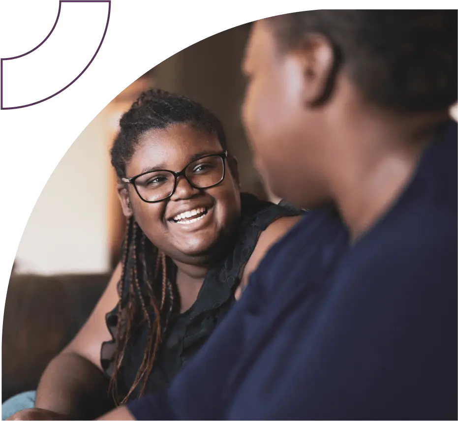 A woman with glasses smiles at a blurred out person in the foreground