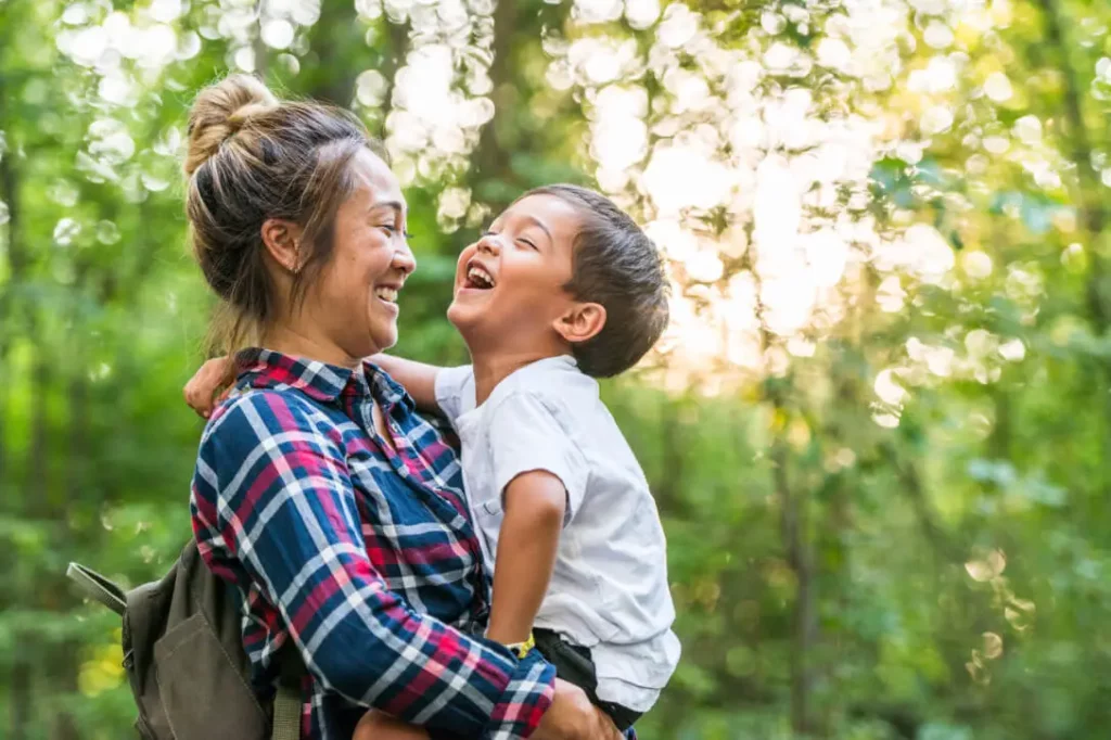 A mother carries a smiling child outdoors.