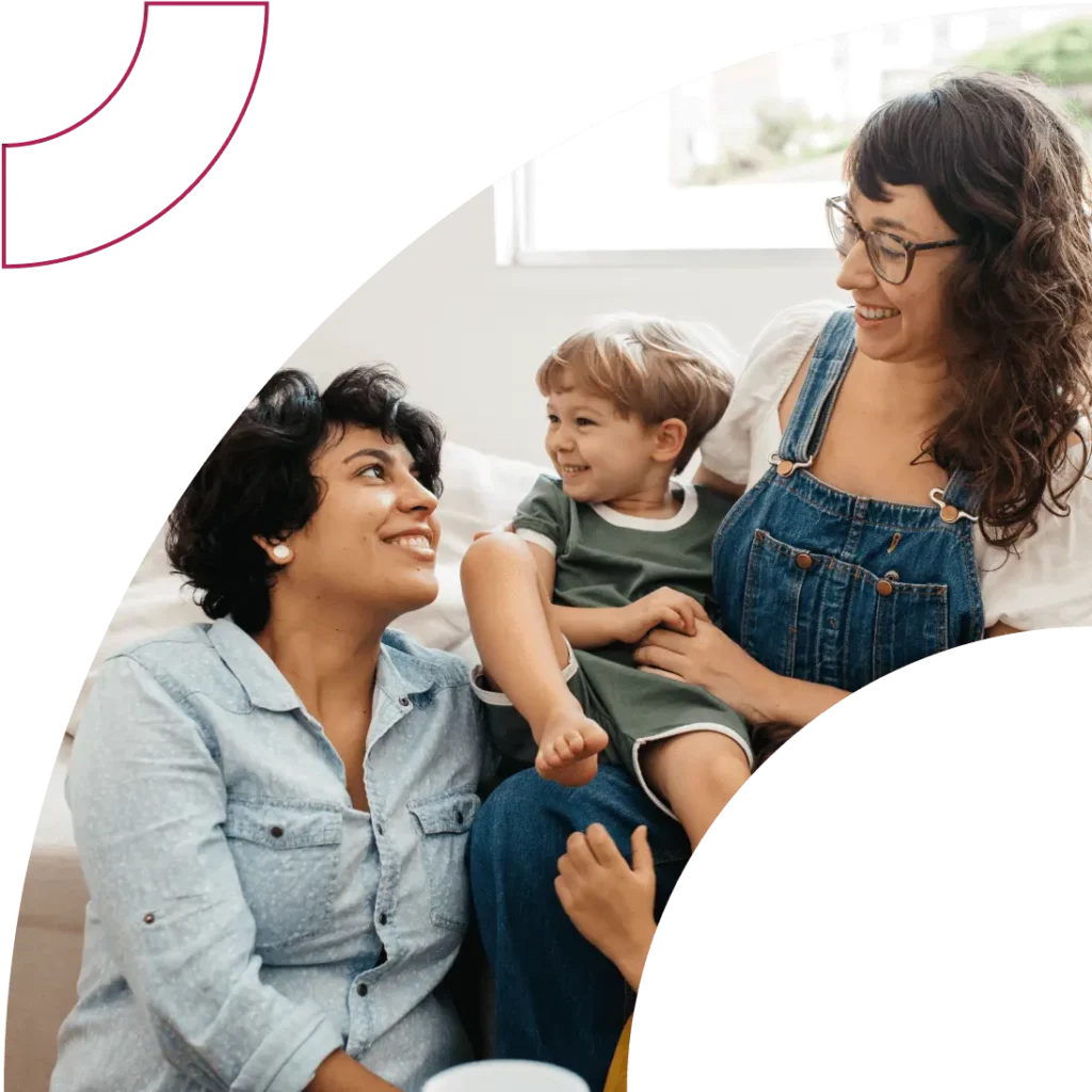 A couple smile on a bed with their child in the middle