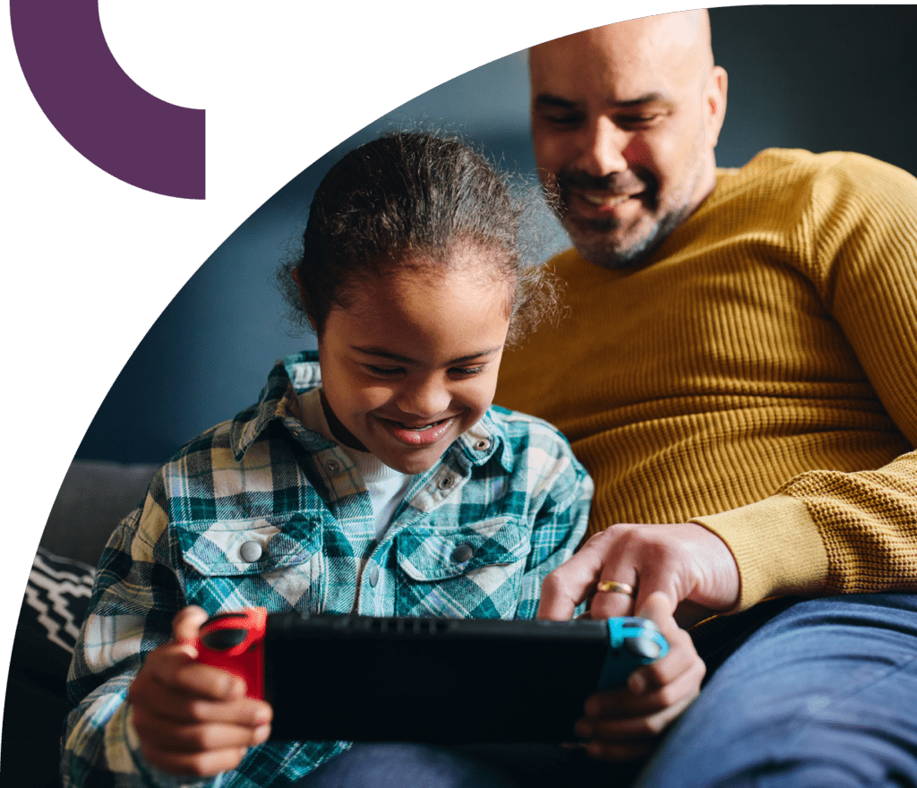 Smiling man and child looking at a video game console.